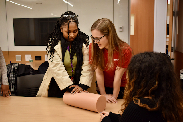 Weill Cornell medical student showing a HPREP student on how to apply pressure to a wound